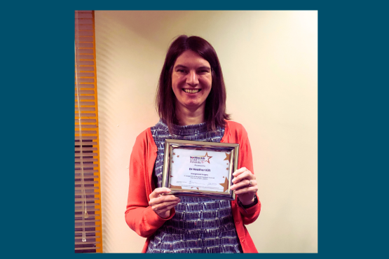 A lady standing looking at the camera holding a certificate