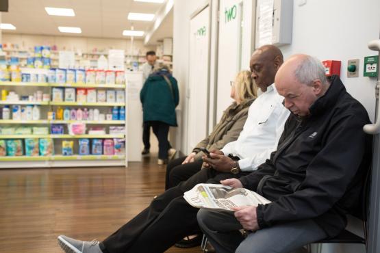 Three people waiting in a pharmacy