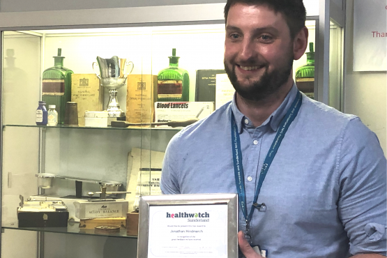 Man smiling at the camera with a certificate award in his hand