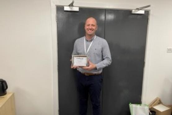 A man holding a Healthwatch Sunderland star award certificate smiling at the camera