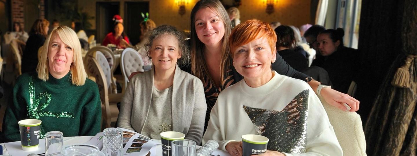 Healthwatch Sunderland staff team sitting at a table smiling at the camera