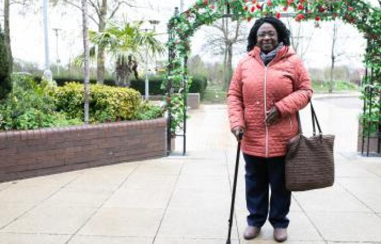 Woman with a walking stick looking at the camera