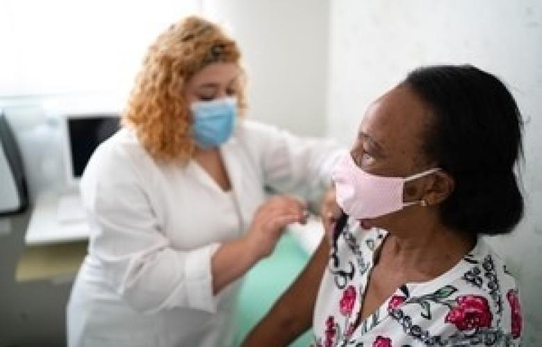 Woman injecting a woman with the COVID-19 vaccine